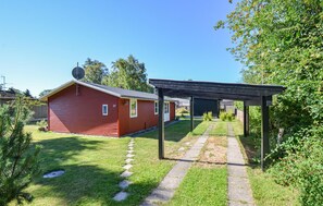 A red wooden house with a garage, a covered outdoor area, and a stone pathway. - 2 bedroom amazing home in Grenaa (Grenaa)