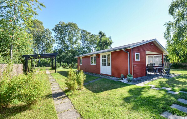 A red single-story house with a covered patio and a small garden area. - 2 bedroom amazing home in Grenaa (Grenaa)