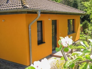 A yellow building with a tiled roof, two windows, and a door.