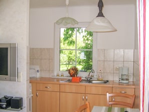 A kitchen with a window, a sink, a coffee maker, and a microwave. - Vacation cottage Bohne, Germany (Kenz-Küstrow)