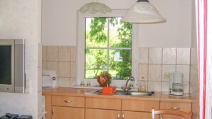 A kitchen with a window, a sink, a coffee maker, and a microwave. - Vacation cottage Bohne, Germany (Kenz-Küstrow)