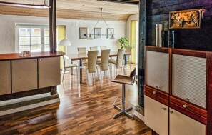 A modern kitchen with wooden flooring, a bar area, and a dining space with chairs and a table.