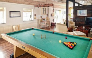 A pool table with balls, a billiard rack, and a wooden table with a label.