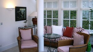 Un espace intérieur accueillant avec des meubles en osier, des coussins à rayures et une table en verre.