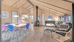 A modern interior with a dining area, sofa, and a wood-burning stove. - Beautiful home in Ringkøbing with sauna (Ringkøbing)
