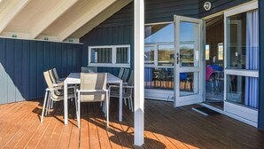 A covered outdoor seating area with a table and chairs, a sliding glass door leading to an interior space, and a view of the outdoors. - Beautiful home in Ringkøbing with sauna (Ringkøbing)