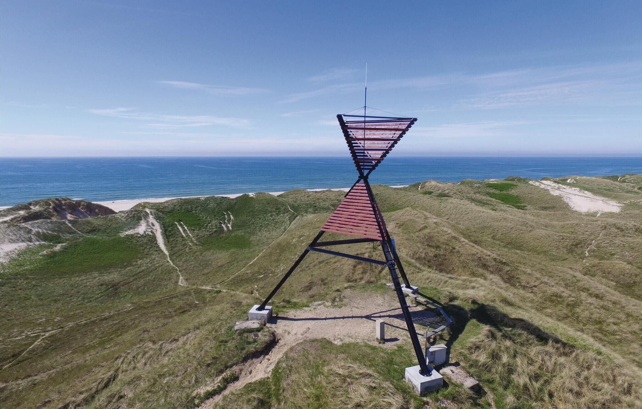 Une tour d’observation unique, dotée d’une plateforme inclinée offrant une vue panoramique sur un paysage côtier.