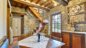 A rustic dining area with a wooden table set for two, a stone wall, and a wooden staircase. - Beautiful home in Cortona (Ar) with outdoor swimming pool (Cortona (Ar))