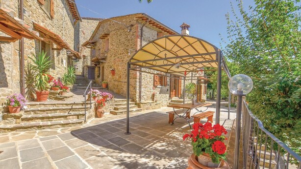 A stone building with a covered patio, steps leading to a wooden door, and potted plants. - Beautiful home in Cortona (Ar) with outdoor swimming pool (Cortona (Ar))