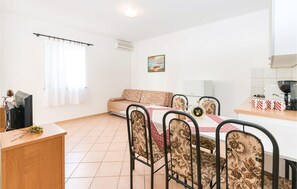 Relax in this stylish living room with a sofa, dining table, and large window.