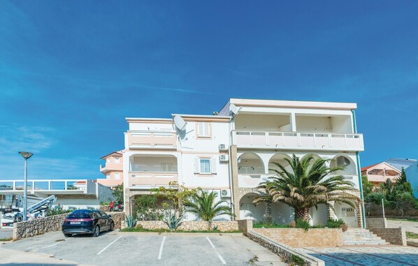 Stylish residential building with a flat roof and large windows, featuring a balcony and lush surroundings.