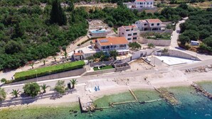 An aerial view of a coastal property with multiple buildings, a swimming pool, and a beach area. - Awesome apartment in Duba (Duba)