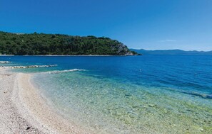 A clear beach with pebbles and a rocky shoreline.