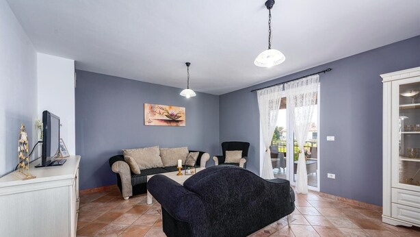 Una sala de estar con un sofá, sillones, un televisor y un aparador.