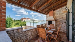 Un patio cubierto con paredes de piedra, una chimenea de ladrillo y una mesa con sillas.