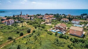 Vista aérea de una zona residencial costera con casas, una iglesia destacada y una vista despejada del mar.