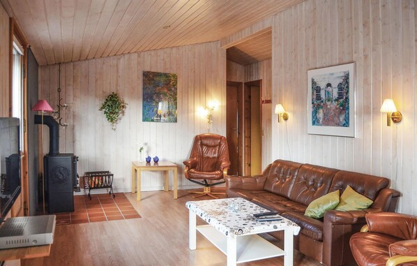 A cozy living room with a fireplace, leather sofa, and a small table with a patterned tablecloth.