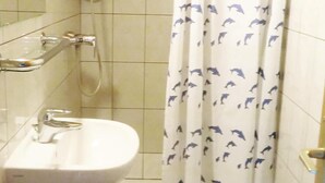 Ein Badezimmer mit einem weißen Waschbecken, einer Dusche mit Duschvorhang mit Delfinmotiv und gefliesten Wänden.