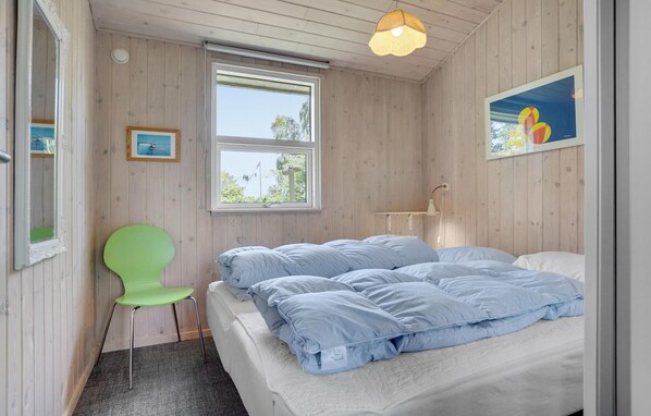 A bedroom with a bed, a window, a chair, and a lamp.