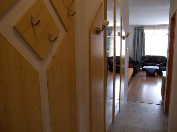 A hallway with wooden doors and a view into a living room with a sofa and a table.