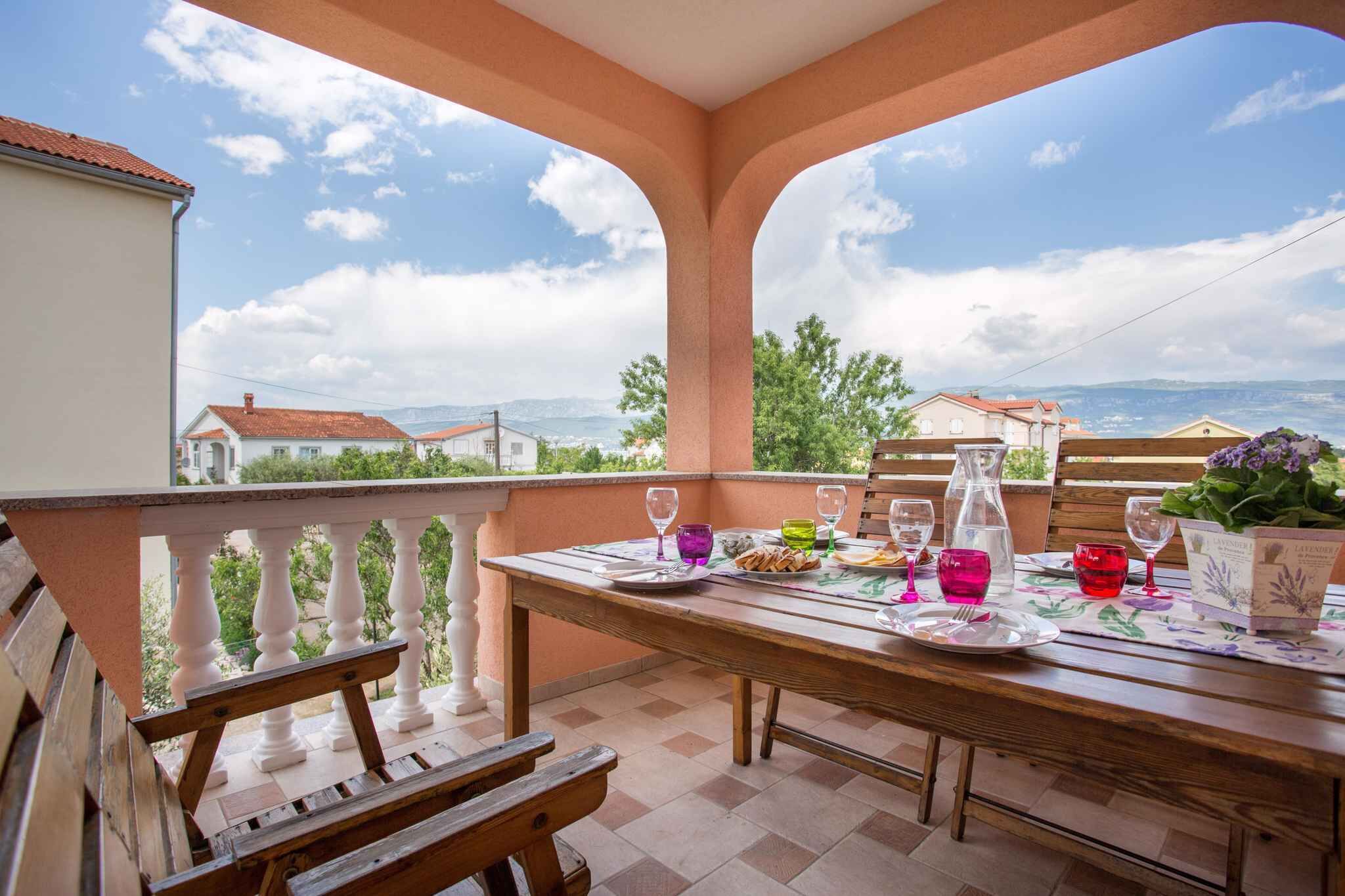 A terrace with a table set for two, overlooking a scenic landscape.
