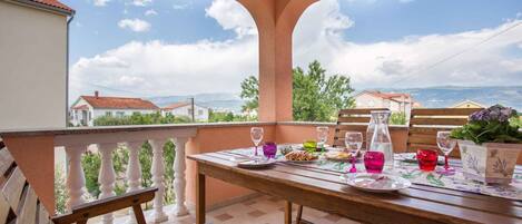 A terrace with a table set for two, overlooking a scenic landscape.