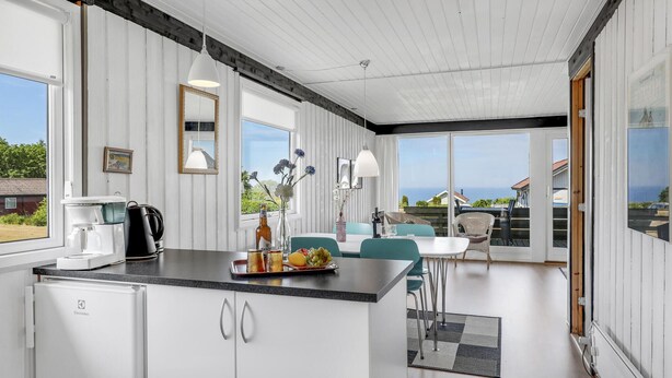 Een moderne keuken met een groot eiland, witte kasten en uitzicht op zee.