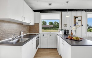 Enjoy a well-lit kitchen with a garden view, sleek cabinetry, and a stainless steel sink.