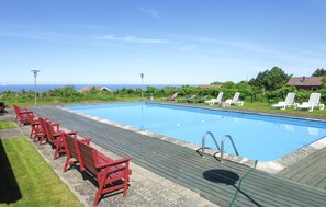 Relax by the pool with ocean views, surrounded by comfortable seating and a wooden deck.