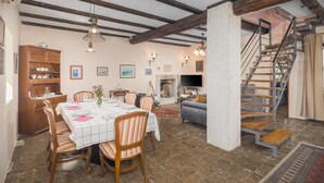 A dining area with a table set for four, surrounded by wooden chairs. A fireplace is visible in the background, and a staircase leads to an upper level. - Stunning home in Vrsar with WiFi (Vrsar)
