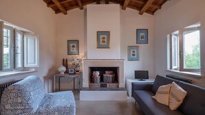 Un salon chaleureux avec une cheminée, un canapé, une petite table agrémentée d’objets décoratifs et des tableaux encadrés accrochés au mur.