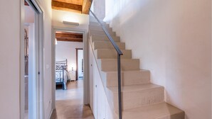 Un escalier avec une rampe métallique menant à une chambre à coucher équipée d’un lit et d’une table de chevet.