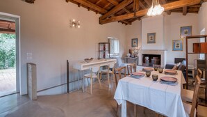 Un espace repas doté d’un plafond en bois, d’une cheminée et d’une table mise pour le repas.