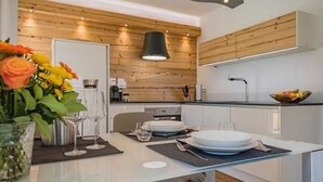 Eine moderne Küche mit Holzvertäfelung, einer weißen Arbeitsplatte und einem Essbereich für vier Personen.