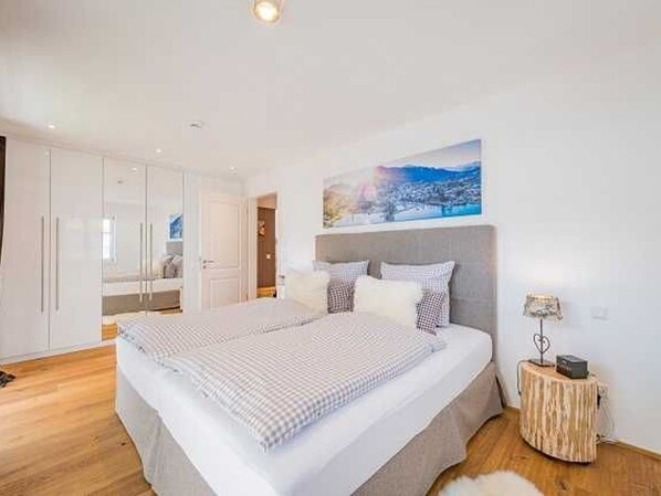 A bedroom with a large bed, a bedside table with a lamp, and a painting on the wall.