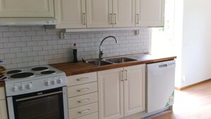 A kitchen with white cabinets, a stove, a sink, and a dishwasher.