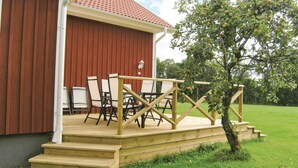 A wooden deck with outdoor furniture, a red building, and a tree with fruit.