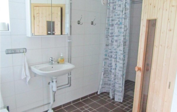 A bathroom with a white sink, a mirror above it, and a shower curtain with text.