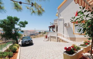 A residential area with a paved driveway, a parked car, and a building with a balcony. - Lovely apartment in Kustici with WiFi (Kustici)