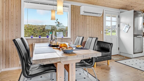 A modern kitchen with a dining table, chairs, and a view through the window.