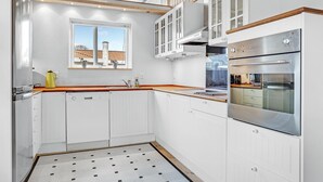 A modern kitchen with white cabinetry, a large window, and a built-in oven.