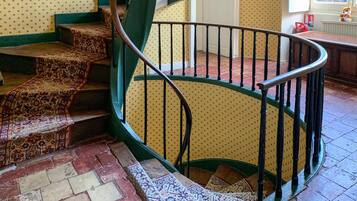 A spiral staircase with a patterned carpet and a green railing.