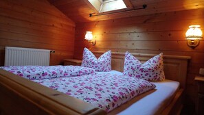 A wooden cabin bedroom with two beds, floral bedding, wall-mounted lights, and a skylight. - Apartment Wallberg - Böcklhof, Kreuth-Brunnbichl (Kreuth)