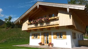 A chalet-style building with a balcony, wooden shutters, and potted plants. - Apartment Wallberg - Böcklhof, Kreuth-Brunnbichl (Kreuth)