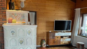 Um quarto acolhedor com teto de madeira, lareira, televisão e um sofá.