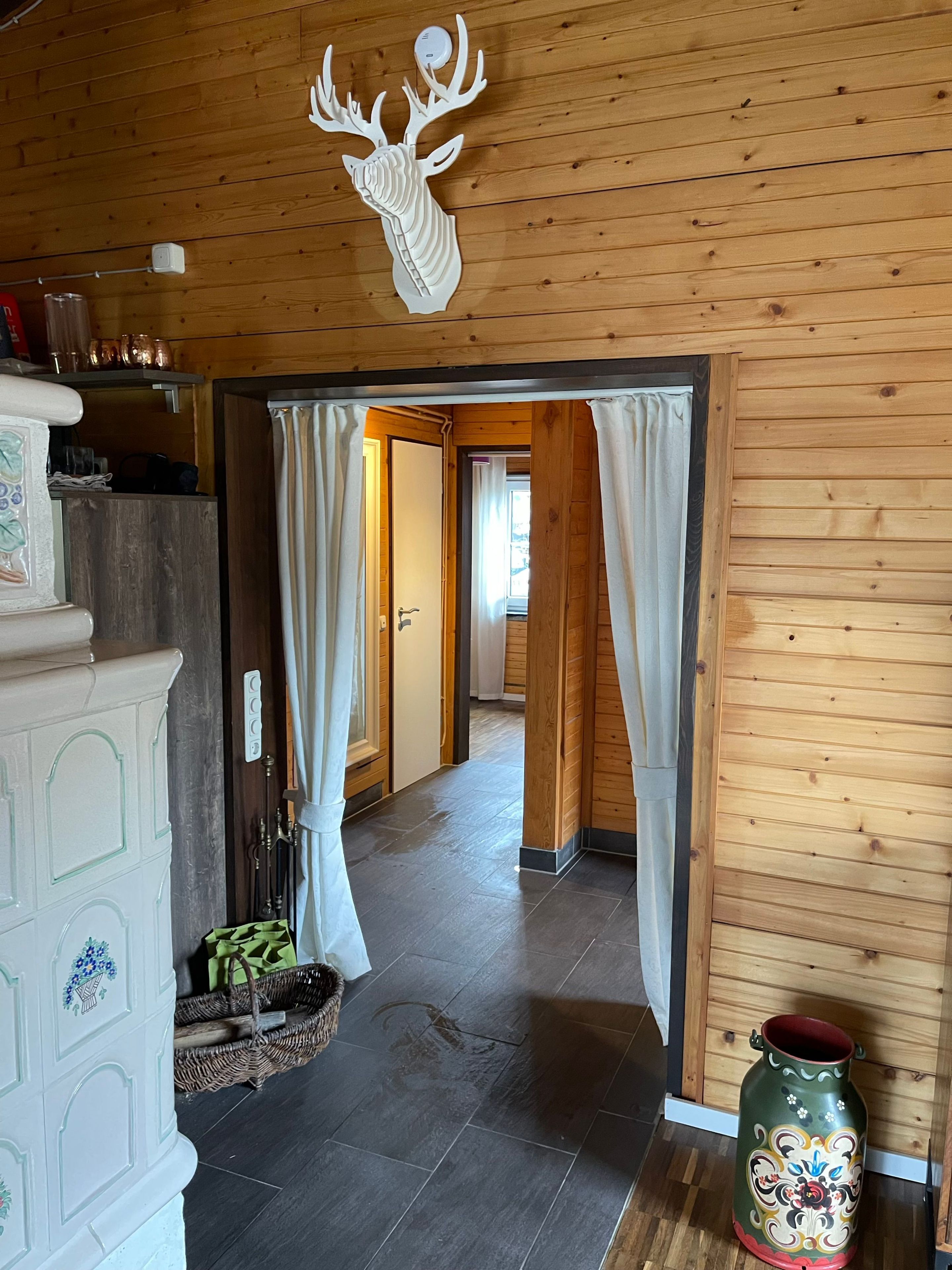Een houten interieur met een decoratie van een hertenkop, een deuropening en een vaas.