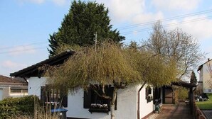 Uma casa branca com cerca de piquete, jardim e um caminho que leva à porta.