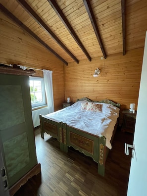 Une pièce en bois avec un lit, une fenêtre avec des rideaux et un radiateur.