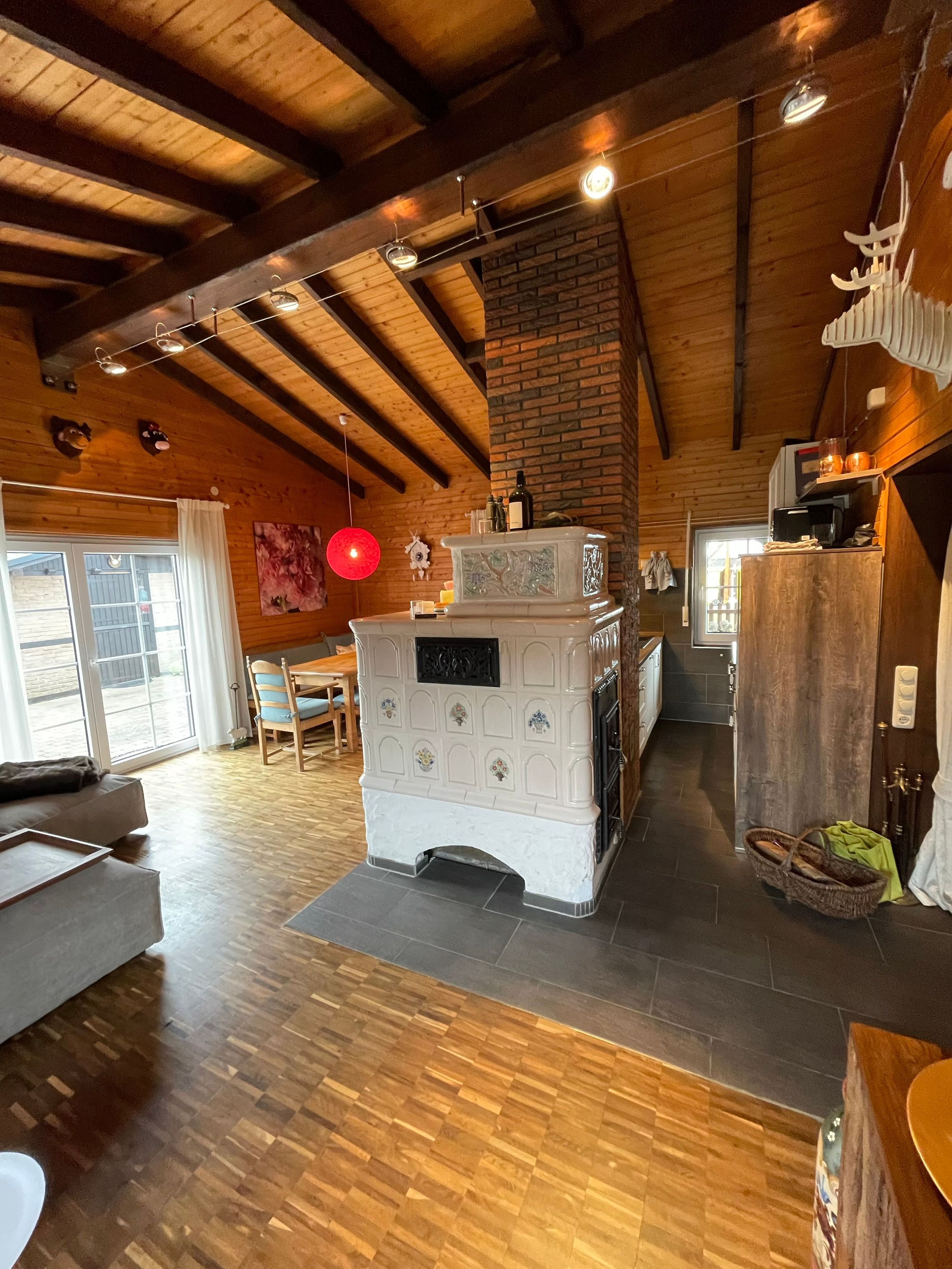 A spacious living area with a fireplace, wooden beams, and a large window.