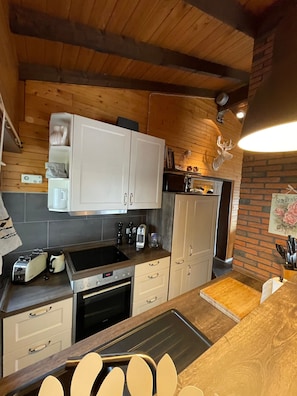 A kitchen with wooden cabinets, a microwave, a toaster, and a sink. - Cozy Eifelhäuschen in the green near Nürburgring - (Hoffeld)